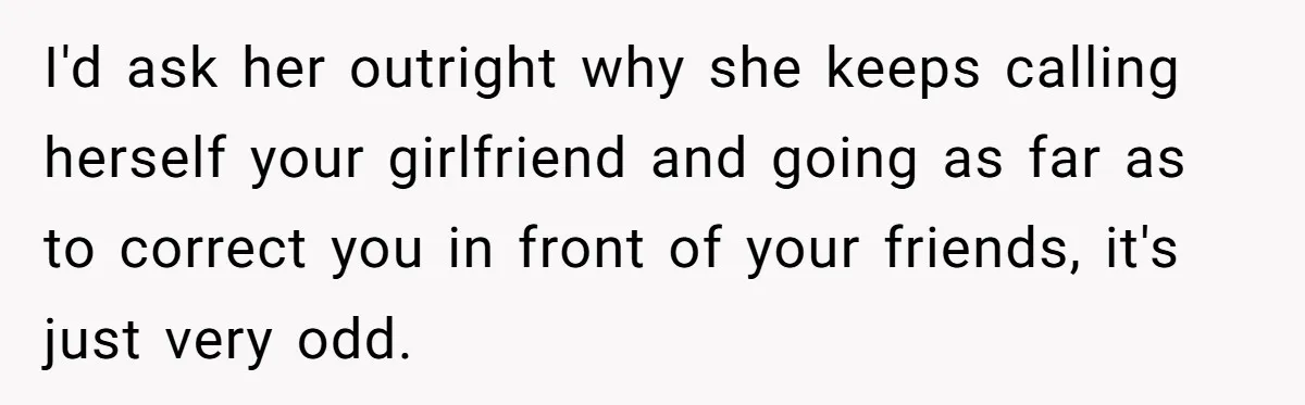 I'd ask her outright why she keeps calling herself your girlfriend and going as far as to correct you in front of your friends, it's just very odd.